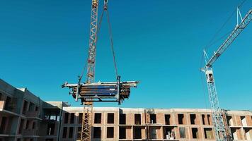 Construction Site with Tower Cranes and Building Framework, A construction site featuring two large cranes lifting materials against video