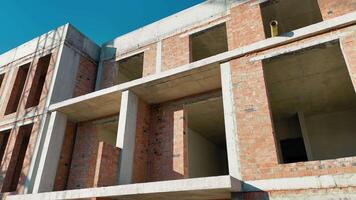 Unfinished Brick Building Under Construction, A partially constructed brick building with exposed concrete beams and open window spaces video