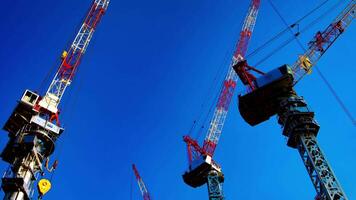 A time lapse of moving cranes behind the blue sky in Tokyo wide shot panning video