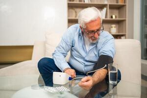 Hypertension problem in senior age. Old man measuring blood pressure with tonometer at home. Senior man have health problem making self checkup. Headache treatment of hypertension hypotension photo