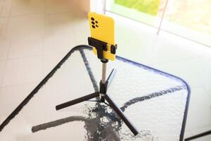 A yellow phone smartphone stands in a phone stand on the table. The concept of communicating from a phone via calling and the Internet, close-up photo