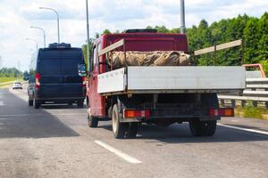 An open flatbed truck drives on a highway in summer. Transportation of goods up to 5 tons. Rental of trucks for regional and international transportation. Copy space for text photo