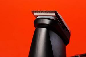 beard trimmer on a red background, close-up. Hair and beard care, close-up photo