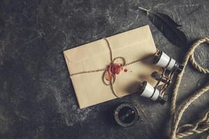 An envelope with a red ribbon tied to it and a pair of binoculars photo