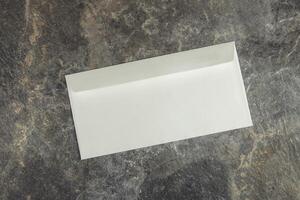 An empty white envelope on a stone surface photo