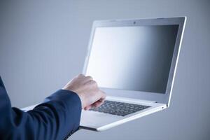 A person in a suit holding a laptop computer photo
