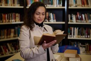 Woman reading a book in a library with shelves in the background photo