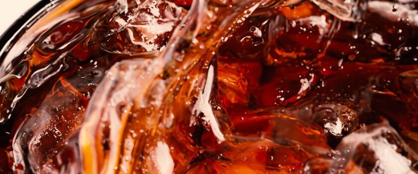 Splashing of Cola and Ice Cola soda and ice splashing fizzing or floating up to top of surface. Close up of ice in cola water. Texture of carbonate drink with bubbles in glass. Cold drink background photo