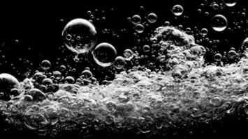 Soda water bubble splashing underwater against black background. photo