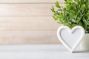 white Photo frame of heart shape for mockup design on light table background.