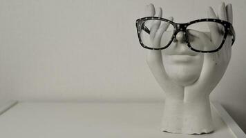 Close-up of a white headless statuette wearing glasses with white dots on a light solid background photo