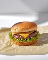 Delicious hamburger with beef patty and lettuce on parchment paper photo