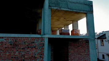 Partial construction of a brick and concrete building, Sunlight streams through the upper level of an unfinished brick and concrete video
