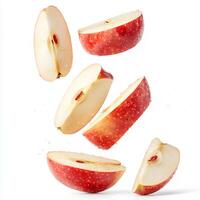 Organic red apple slices flying mid-air against a white background creating a dynamic and fresh visual ideal for healthy lifestyle and nutritious food campaigns photo