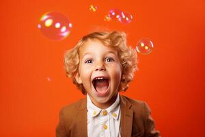 Portrait of a surprised child with soap bubbles on orange background photo