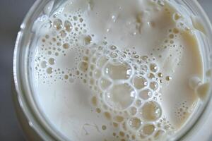 Milk with bubbles creating interesting patterns in glass jar photo