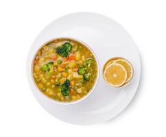 Delicious vegetable soup served in a bowl with lemon slices on the side photo