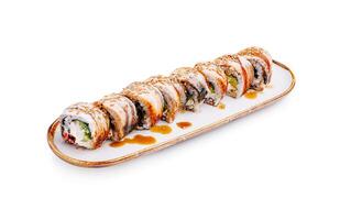 Unique sushi roll presentation with sesame seeds and drizzled sauce at a stylish dining setting photo