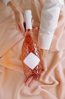 Elegant rose wine bottle held against soft pastel fabric, capturing a moment of celebration and indulgence photo