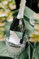 Elegant champagne bottle in an ice bucket surrounded by greenery and fine glassware photo