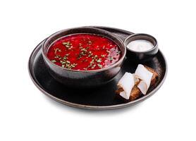 Traditional beet soup served with bread and cream in a rustic bowl photo
