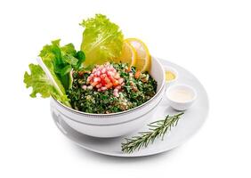 Fresh tabbouleh salad made with parsley, tomatoes, and lemon served in a stylish bowl on a white plate photo