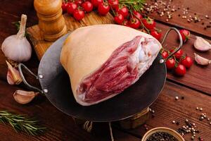 Fresh meat cut displayed on a wooden table surrounded by herbs and vegetables photo