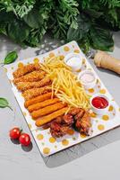 Delicious platter of chicken, fries, and snacks arranged on a colorful plate photo