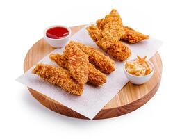 Crispy fried chicken tenders served with dipping sauce and coleslaw on a wooden platter at a casual dining setting photo