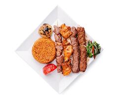 Delicious assorted kebabs served with bulgur, grilled tomatoes, and a fresh side salad in a modern presentation photo