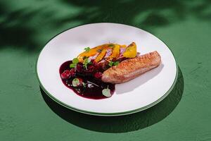 Culinary masterpiece featuring roasted duck breast with berry sauce and citrus garnish served on white plate photo