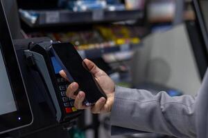 Close-up image showing contactless payment with smartphone. Person using digital wallet for transaction at retail store. Concept of cashless payments, convenience, and modern technology. photo