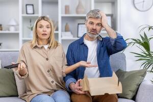 A confused couple feeling unsure about their recent purchase at home, facing difficulty with online shopping or delivery, and showing perplexed expressions. photo