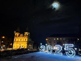 Illuminated 2025 display with festive winter setting in a city square at night photo