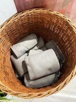 Wicker basket containing neatly folded gray towels in a well-lit setting photo