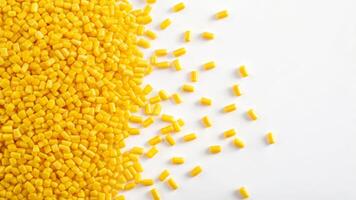 Yellow plastic granules scattered on white surface material study industrial environment close-up view photo