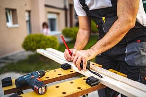 Unrecognizable men measuring wooden plank outdoors photo