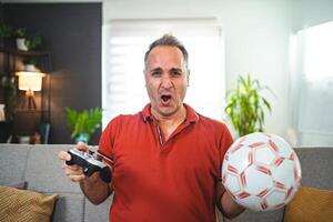 Worried middle aged man playing soccer game at home photo