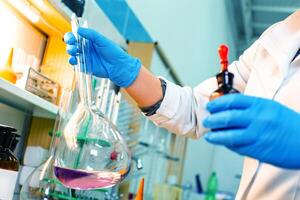 Researcher conducts chemical experiment with flask and reagent in laboratory setting photo