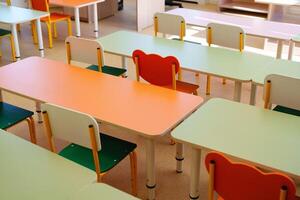 Brightly colored classroom furniture arranged in a learning space with empty desks and chairs during school hours photo