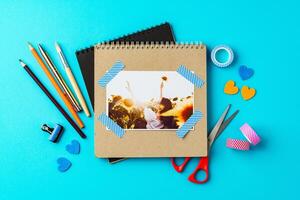 Creative workspace with scrapbook tools and a joyful photo resting on a bright blue surface