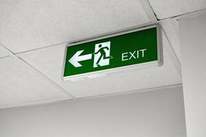 Clear exit sign directing individuals to the left in a well-lit indoor environment photo