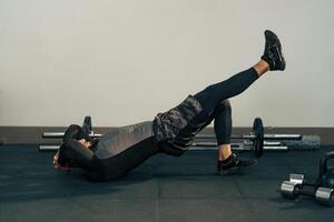 Fitness enthusiast performs leg raises on a gym mat during a workout session focusing on core strength and stability photo
