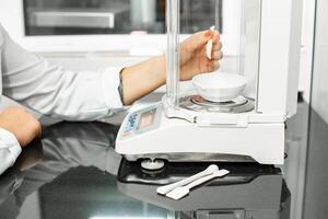 Precision weighing technique in a laboratory setting with a digital balance and measuring tools in use photo