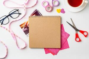 Creative workspace with scrapbook materials and a cup of tea on a bright surface photo