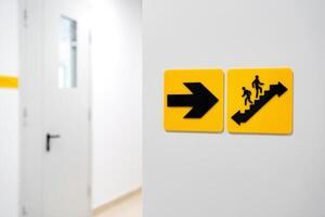 Directional signs indicate stairway and exit in a modern building hallway photo