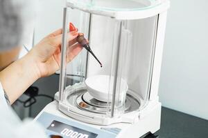 Precision weighing of liquid in a laboratory setup with an analytical balance during a research experiment photo