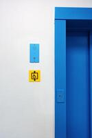 Bright blue elevator entrance features accessibility sign and intercom in a modern building photo
