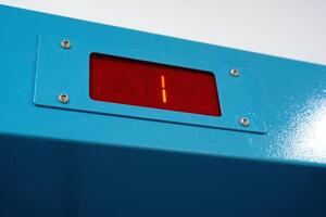 Digital display shows a countdown of one on a bright blue panel mounted on a wall in a contemporary setting photo