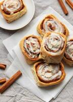 Delicious cinnamon rolls topped with icing and almonds on baking paper photo